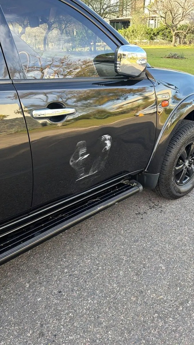 Antes: Mitsubishi L200 gris con abolladuras en la puerta trasera